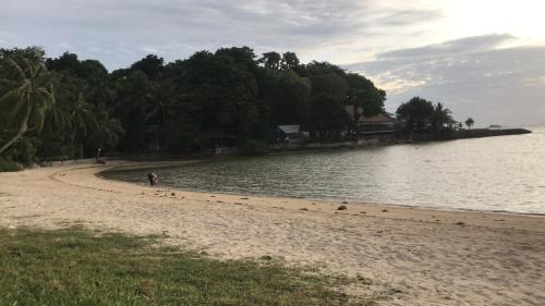 a person walking on a beach next to the water at Smiley Bungalows Guesthouse in Srithanu