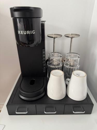 a coffee maker with two cups on a black tray at Le 900 Tremblant Inn Café and Bistro in Mont-Tremblant