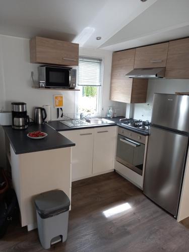 une cuisine avec un réfrigérateur et des armoires en acier inoxydable dans l'établissement Mobil HOME 40 m2 3CH, à Pont-Aven