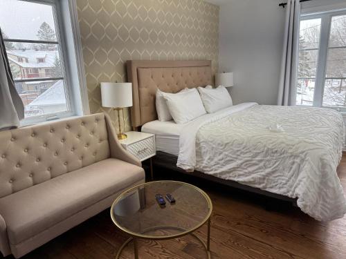 a bedroom with a bed and a couch and a table at Le 900 Tremblant Inn Café and Bistro in Mont-Tremblant