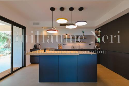 - une cuisine avec un îlot bleu dans l'établissement VILLA CASADELMAR- 7 chambres, 16 personnes, vue mer, piscine, appartement, accès plage, terrain pétanque, à Coti-Chiavari