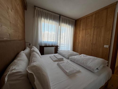 a bedroom with a large white bed with a window at Appartamento vista Dolomiti in Pieve di Cadore