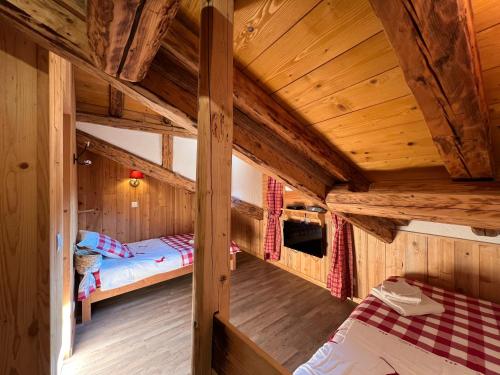 une chambre avec deux lits dans une cabane en bois dans l'établissement Chalet cosy pour 13 sauna, à Saint-Martin-de-Belleville