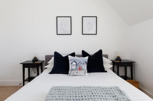 a bedroom with a white bed with black pillows at Gorgeous home for 12 - Walk to Beach - Sea View in Chichester