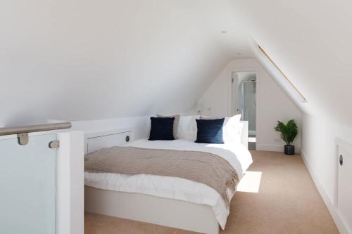 a white bedroom with a bed with blue pillows at Gorgeous home for 12 - Walk to Beach - Sea View in Chichester