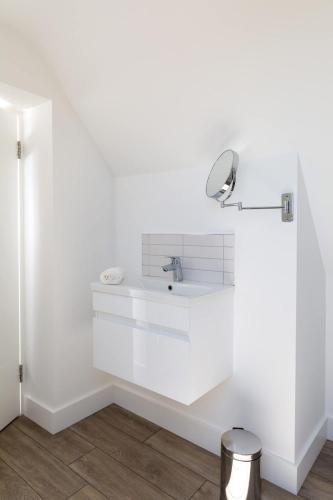 a white bathroom with a sink and a mirror at Gorgeous home for 12 - Walk to Beach - Sea View in Chichester