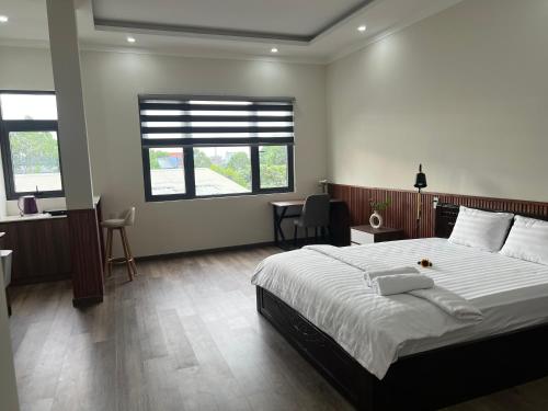 a bedroom with a bed and a desk and windows at The Sun Hotel in Long Bình