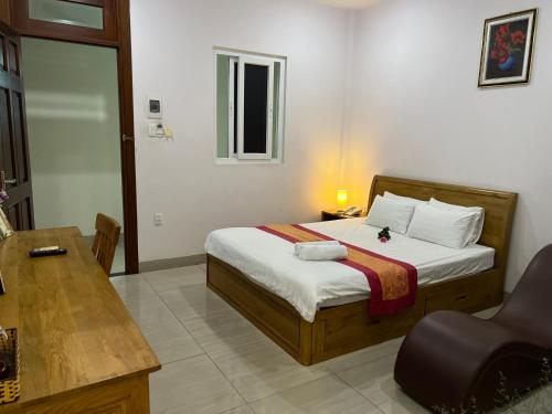 a bedroom with a bed with a desk and a chair at The Sun Hotel in Long Bình