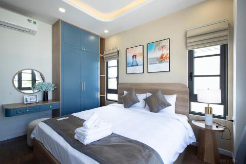 a bedroom with a large white bed with blue cabinets at The Sun Hotel in Long Bình