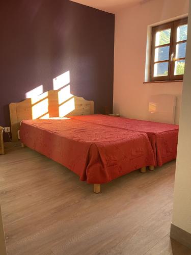 une chambre avec un lit avec une couverture rouge dessus dans l'établissement Location Logement T3 à Vignec dans les Pyrénées, à Vignec