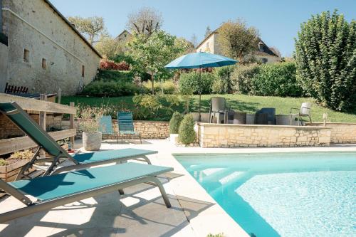 - une piscine avec 2 chaises longues et un parasol dans l'établissement Coeur de village, maison pour 8 avec piscine, à Coly