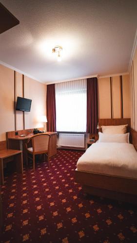 a hotel room with a bed and a desk at Hotel Resi Beverungen in Beverungen