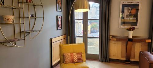 une chaise jaune dans une chambre avec fenêtre dans l'établissement Superbe appartement 132m2, classé 5 étoiles, Sarlat centre, à Sarlat-la-Canéda