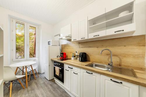 une cuisine avec des armoires blanches et un évier dans l'établissement Charmant cocon au cœur de Rennes calme et lumineux, à Rennes