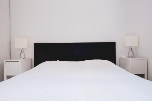 - un grand lit blanc avec deux lampes latérales dans l'établissement Villa avec vue sur le lac Domaine de Pitrot, à Lacanau