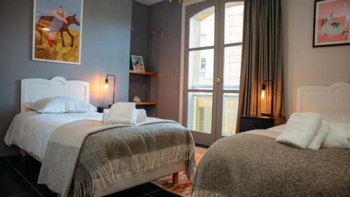 a bedroom with two beds and a window at Superbe appartement traversant 132m2, classé 5 étoiles, Sarlat centre in Sarlat-la-Canéda