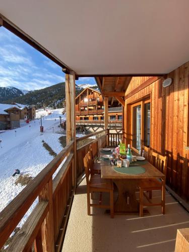une terrasse en bois avec une table et des chaises sur une piste de ski dans l'établissement Le Cocon des Airelles - Meublé de tourisme 3 étoiles au pied des pistes avec garage, à Montgenèvre
