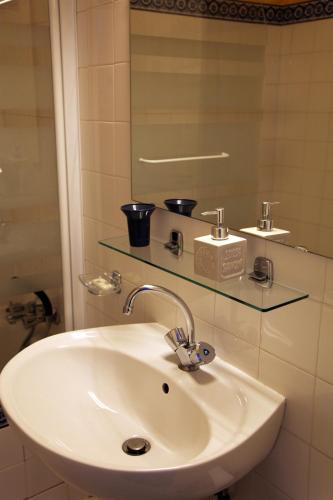 un lavabo blanc dans une salle de bain avec un miroir dans l'établissement DOMAINE DU SIESTOU WINE RESORT & spa, à Laure-Minervois