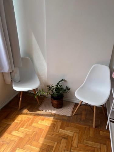 two white chairs and a potted plant in a room at Praia de Botafogo vista Pão de Açúcar in Rio de Janeiro