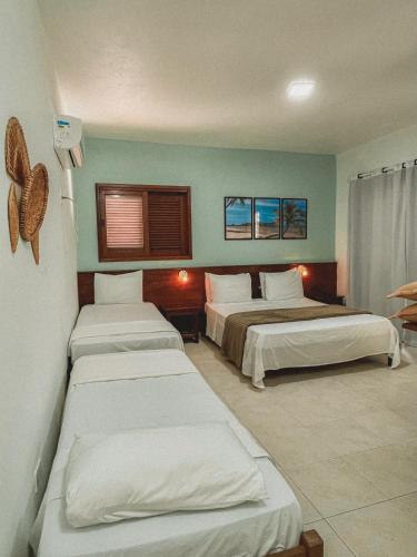 a hotel room with three beds in it at Pousada Maliale in Ilha de Boipeba