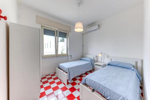 a bedroom with two beds and a red and white checkered floor at Le Carrube Vista Mare in Andrano