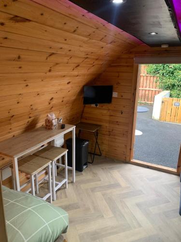 a room with a wooden wall with a desk and a television at Smugglers Cove in Widows Row