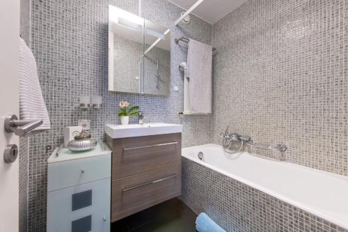 um banheiro com uma banheira branca, uma pia e uma banheira tubermott em Apartment Kandahar 42 em Crans-Montana