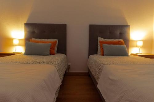 a bedroom with two beds with pillows and two lamps at Gustavo's Place in Sines