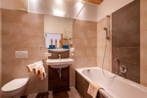 a bathroom with a sink and a toilet and a bath tub at Pension Noella in Sankt Johann in Tirol