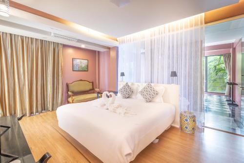 a bedroom with a large white bed with flowers on it at See Sea Villa Phuket SHA in Patong Beach
