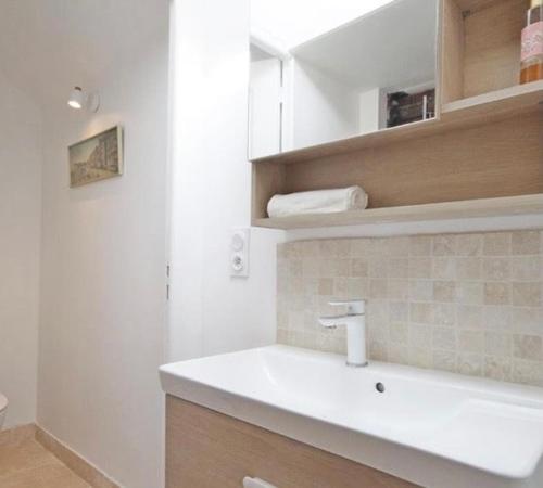 une salle de bain blanche avec un lavabo et un miroir dans l'établissement Gîte du rouge gorge Normandy, à Illeville-sur-Montfort