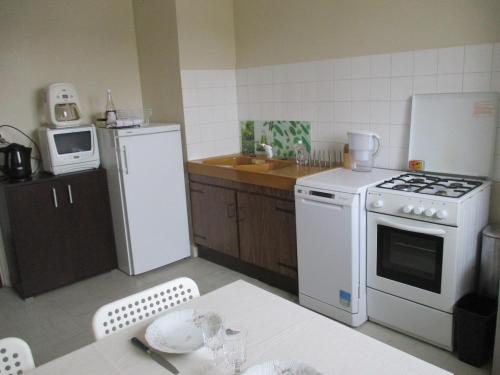 La cuisine est équipée d'une cuisinière blanche et d'un réfrigérateur. dans l'établissement APPARTEMENT AU COEUR D'Huelgoat, à Huelgoat