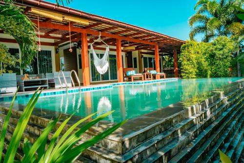 a swimming pool in front of a house at Farinda Resort & Pool Villa in Ban Huai Muang