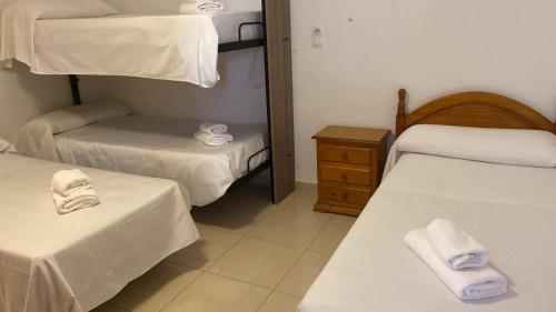 a room with two beds and a dresser with towels at Hospedium DLJ Hostal Ben Nassar in Arjona