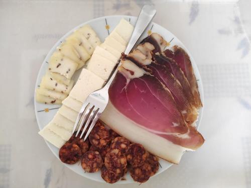 a plate of cheese and nuts with a fork and knife at Őrségi Tornácos Vendégfogadó in Felsőszenterzsébet