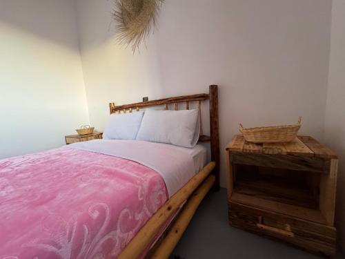 a bedroom with a wooden bed with a pink blanket at Fisherman house rooms in Wassane