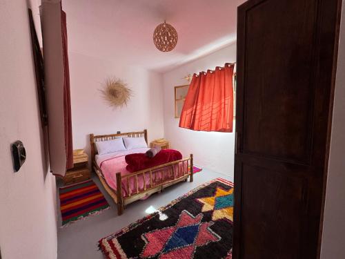 a bedroom with a bed with a red blanket and a rug at Fisherman house rooms in Wassane