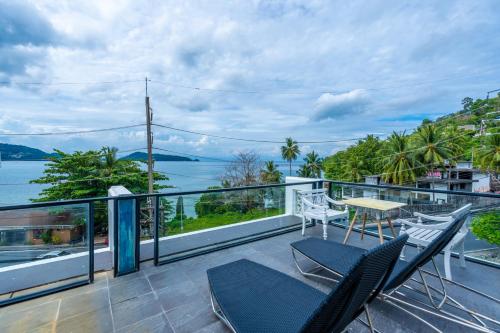a balcony with chairs and a table and a view of the water at See Sea Villa Phuket SHA in Patong Beach