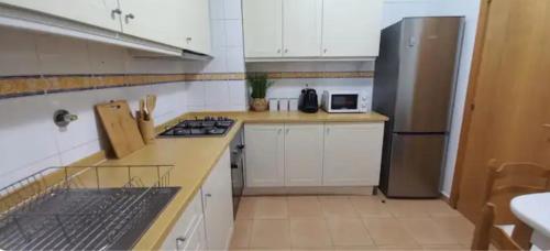 a kitchen with white cabinets and a stainless steel refrigerator at Cozy apartment in Madeira Island in Ribeira Brava