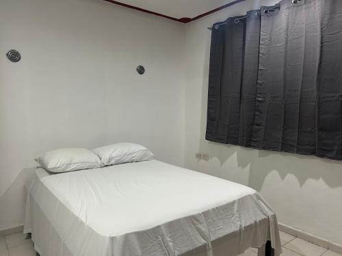 a white bed in a room with black curtains at Hostel Treebu in Valladolid