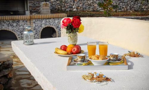 a table with a tray of fruit and a vase of flowers and drinks at Villa Poseidon Residence in Skinária