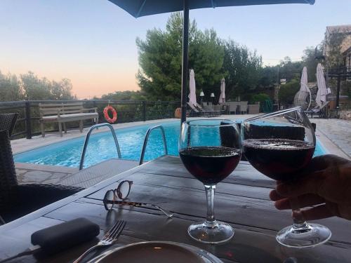 two glasses of wine sitting on a table next to a pool at Villa Poseidon Residence in Skinária