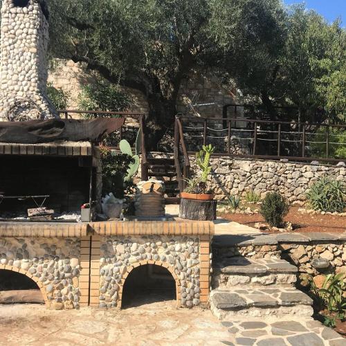 a garden with a stone wall and a stone bridge at Villa Poseidon Residence in Skinária