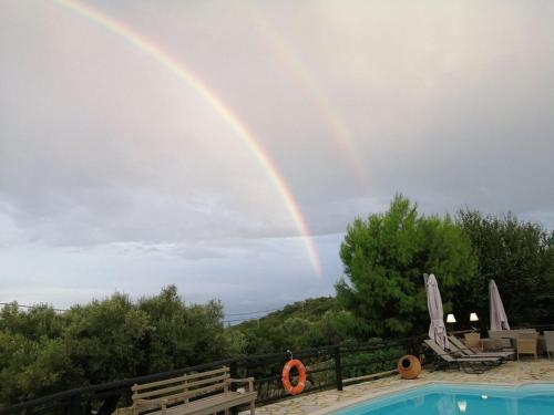a rainbow in the sky over a swimming pool at Villa Poseidon Residence in Skinária