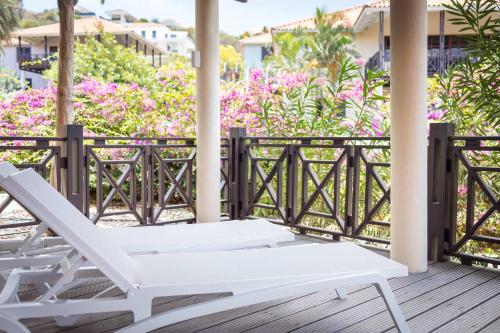 a white lounge chair on a deck with flowers at The Village at Blue Bay Golf & Beach Resort in Sint Michiel