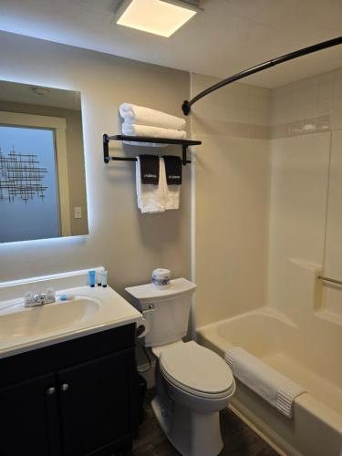a bathroom with a toilet and a sink and a tub at Gunstock Inn & Suites in Gilford