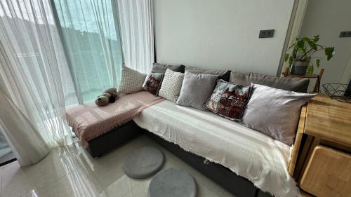 a couch with pillows in a room with a window at Patong Sea View pool view condo in Patong Beach