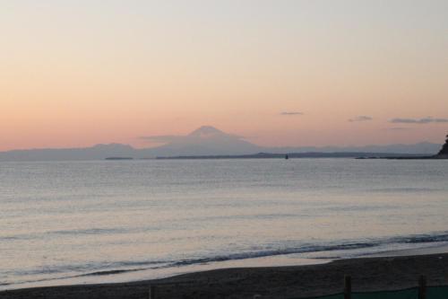 a view of a mountain from the beach at sunset at Friendly Guest House Kawakin in Minamiboso