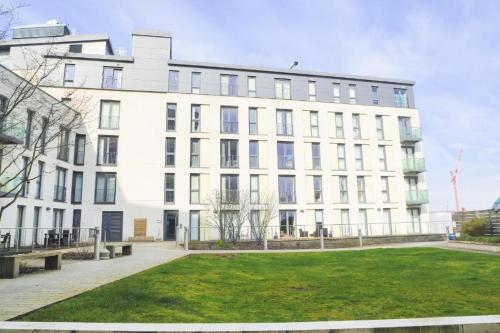 a white building with a lawn in front of it at City Centre Flat within the Hayes Complex in Cardiff