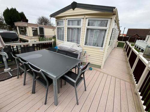 a table and chairs on a deck with a tiny house at Long Beach Park Caravan, Hembsy in Great Yarmouth